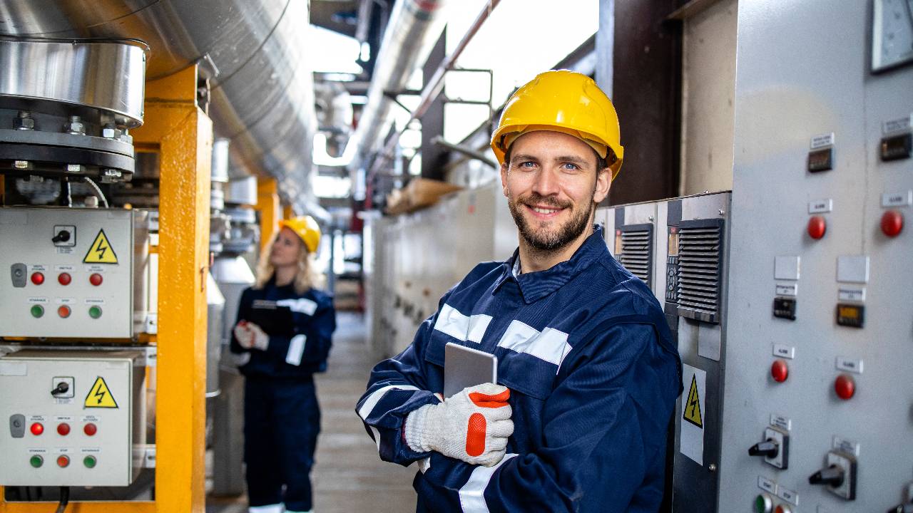 Portrait of an industrial electric engineer standing by power supply