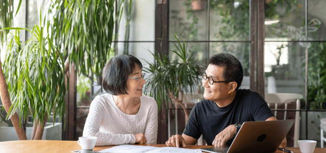 Two people sitting at a table, smiling at each other.